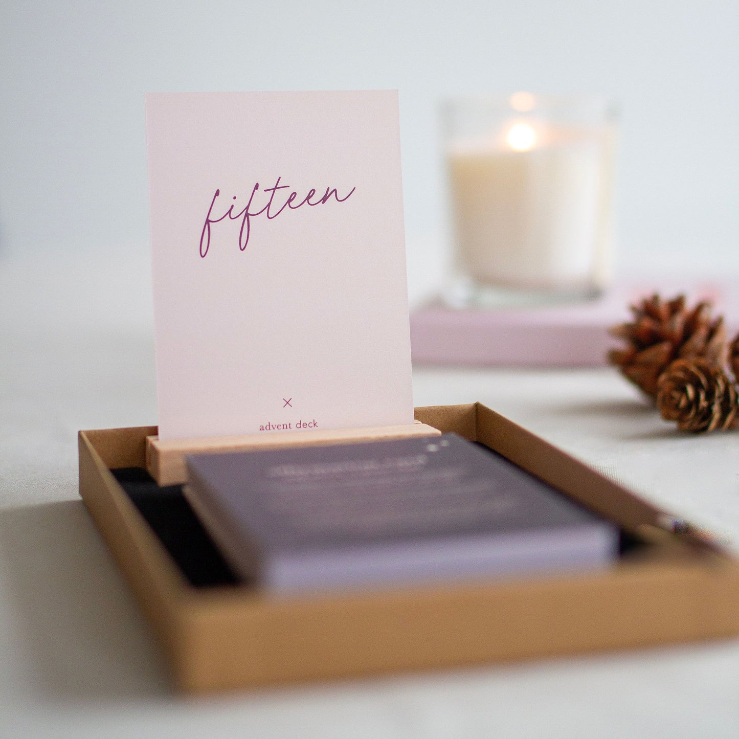 affirmation card advent calendar day fifteen shown placed in the wooded display stand, a candle and journal are out of focus in the background