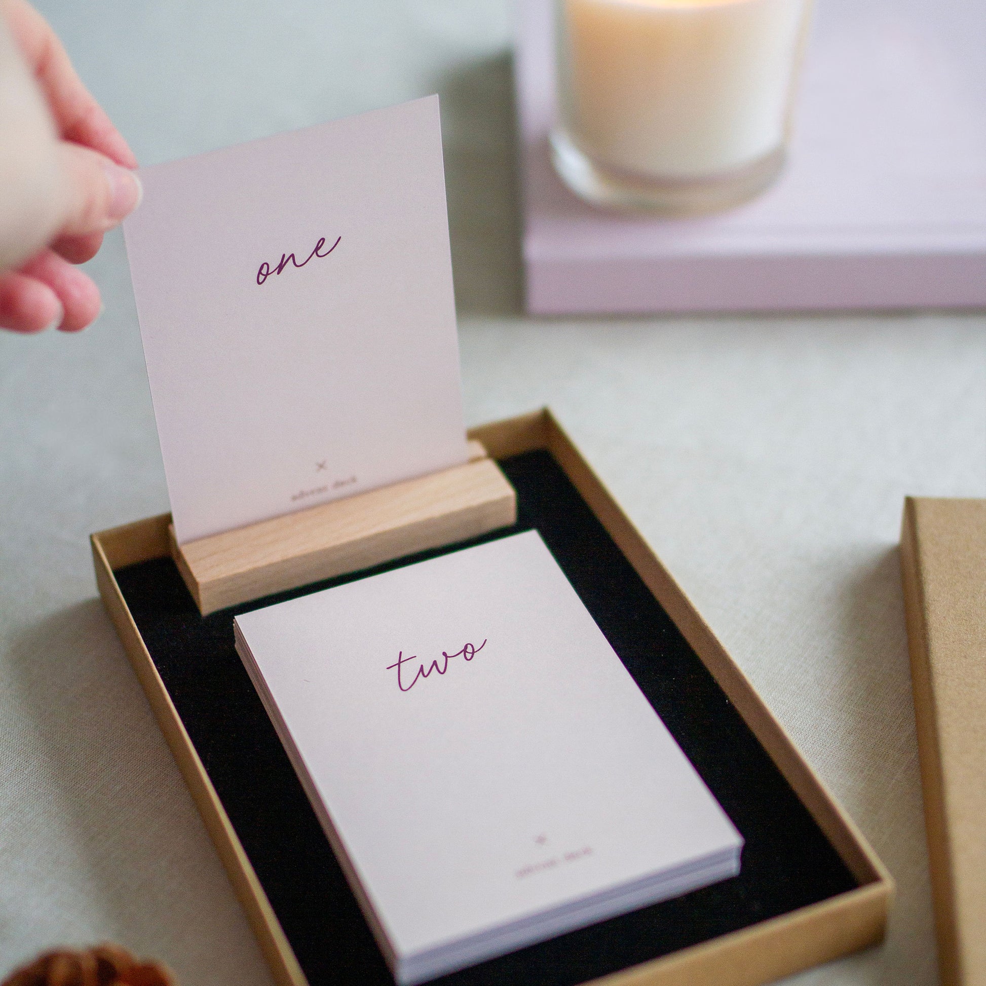 a hand placing advent card number one in the wooden display stand, card number two is waiting to be "opened" turned over the next day